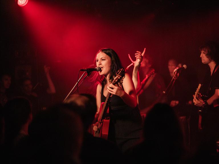 Musikerin bei einem kleinen Konzert unter rotem Bühnenlicht